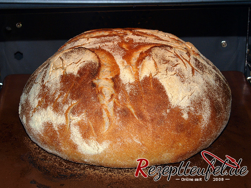 Das Brot nach halber Garzeit auf dem Backstein, die Oberfläche ist aufgebrochen