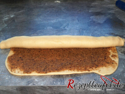 Der ausgerollte und mit Füllung bestrichene Teig wird aufgerollt