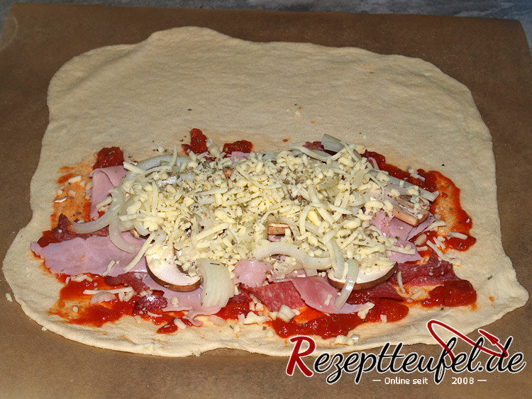 Der ausgerollte Pizzateig wird belegt